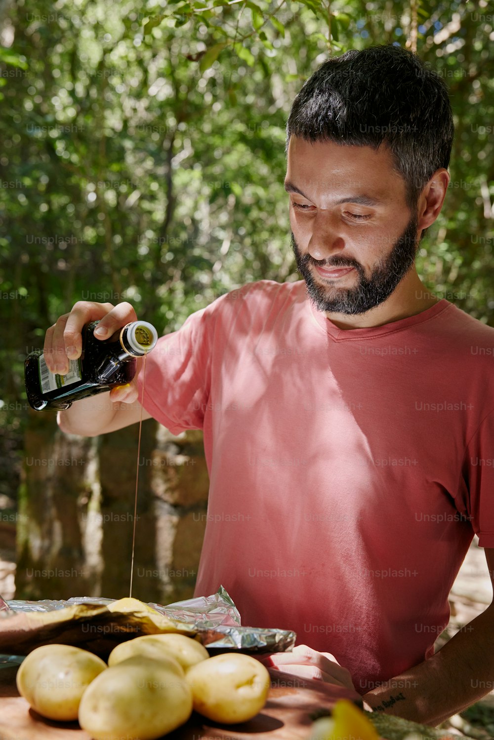 um homem com barba está derramando algo em uma garrafa