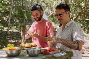 a couple of men standing next to each other in front of a table