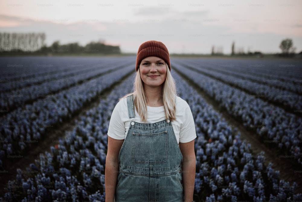 uma mulher de pé em um campo de flores azuis