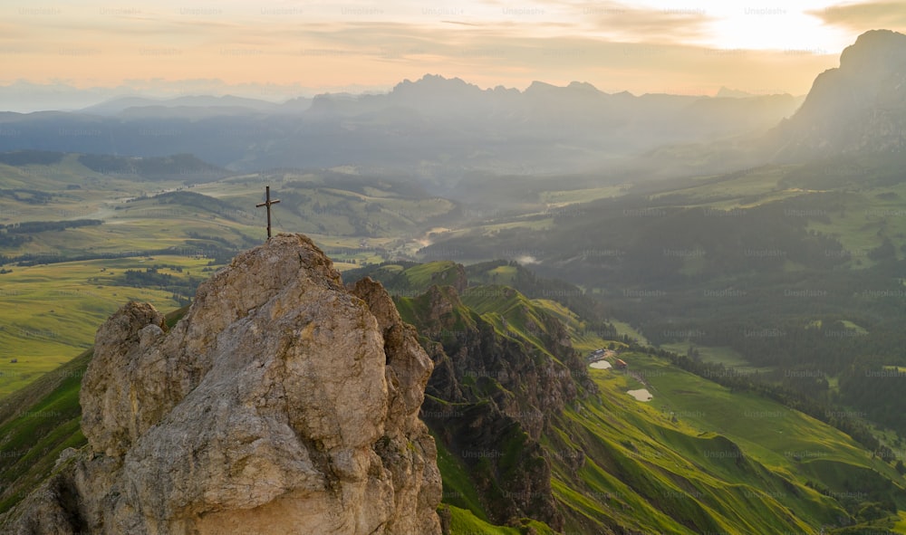 a person standing on top of a mountain with a cross