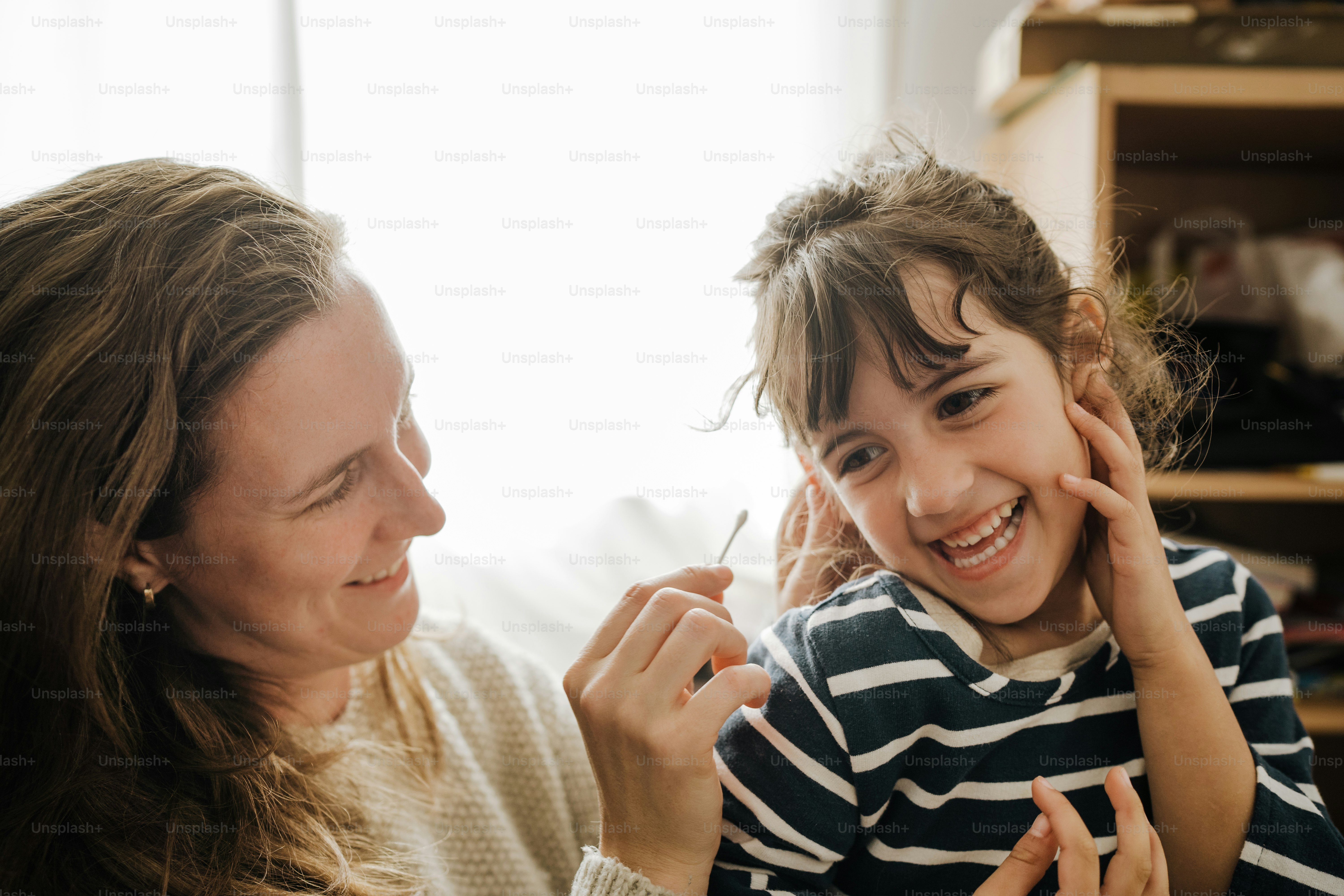 a woman holding a little girl with a toothbrush in her mouth