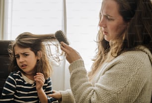 a woman combing a little girl's hair with a brush