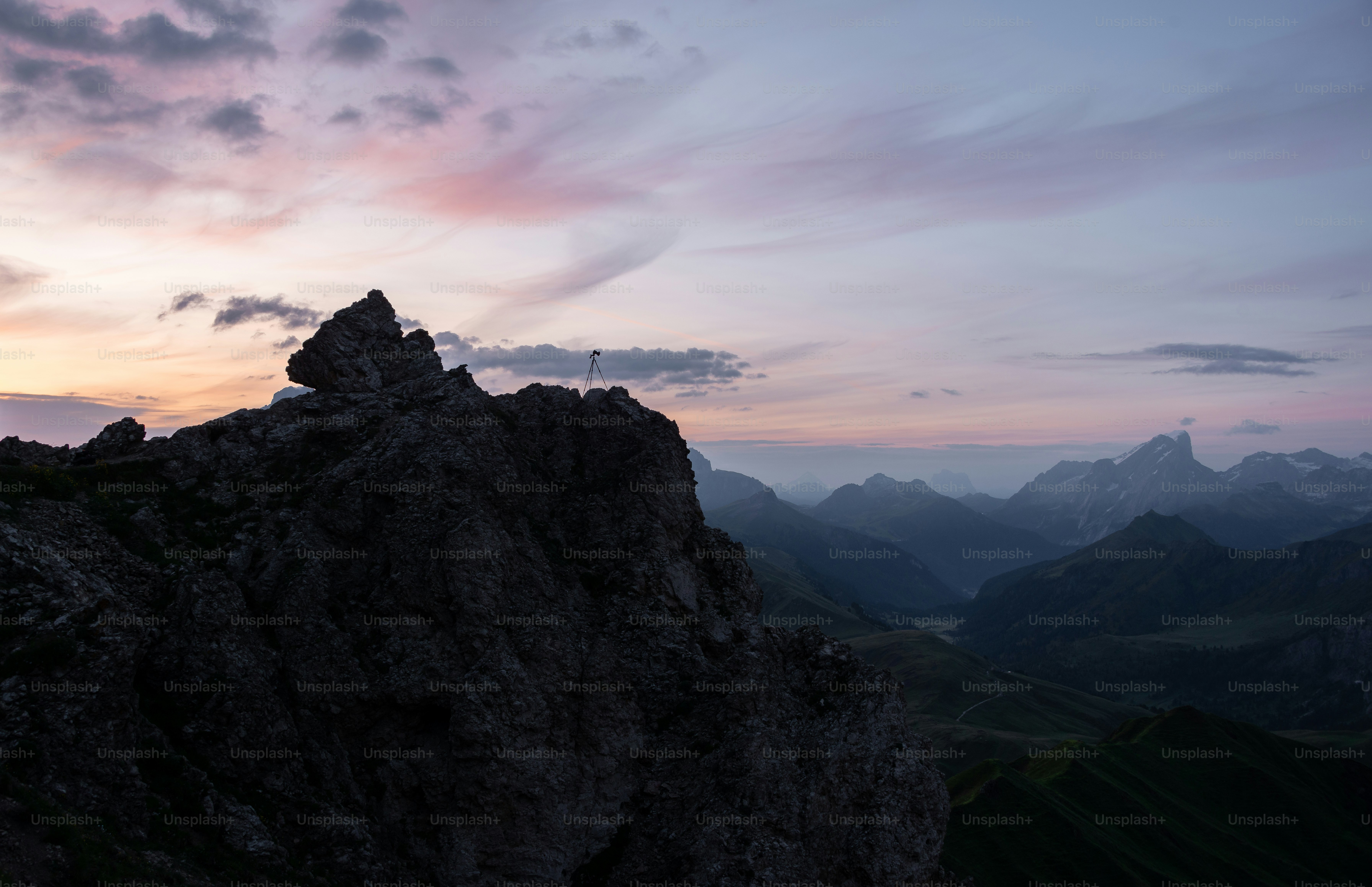 uma pessoa em pé no topo de uma montanha ao pôr do sol