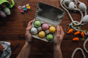 a person holding an egg carton filled with colored eggs