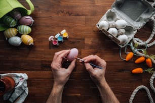 a person painting an egg on a wooden table