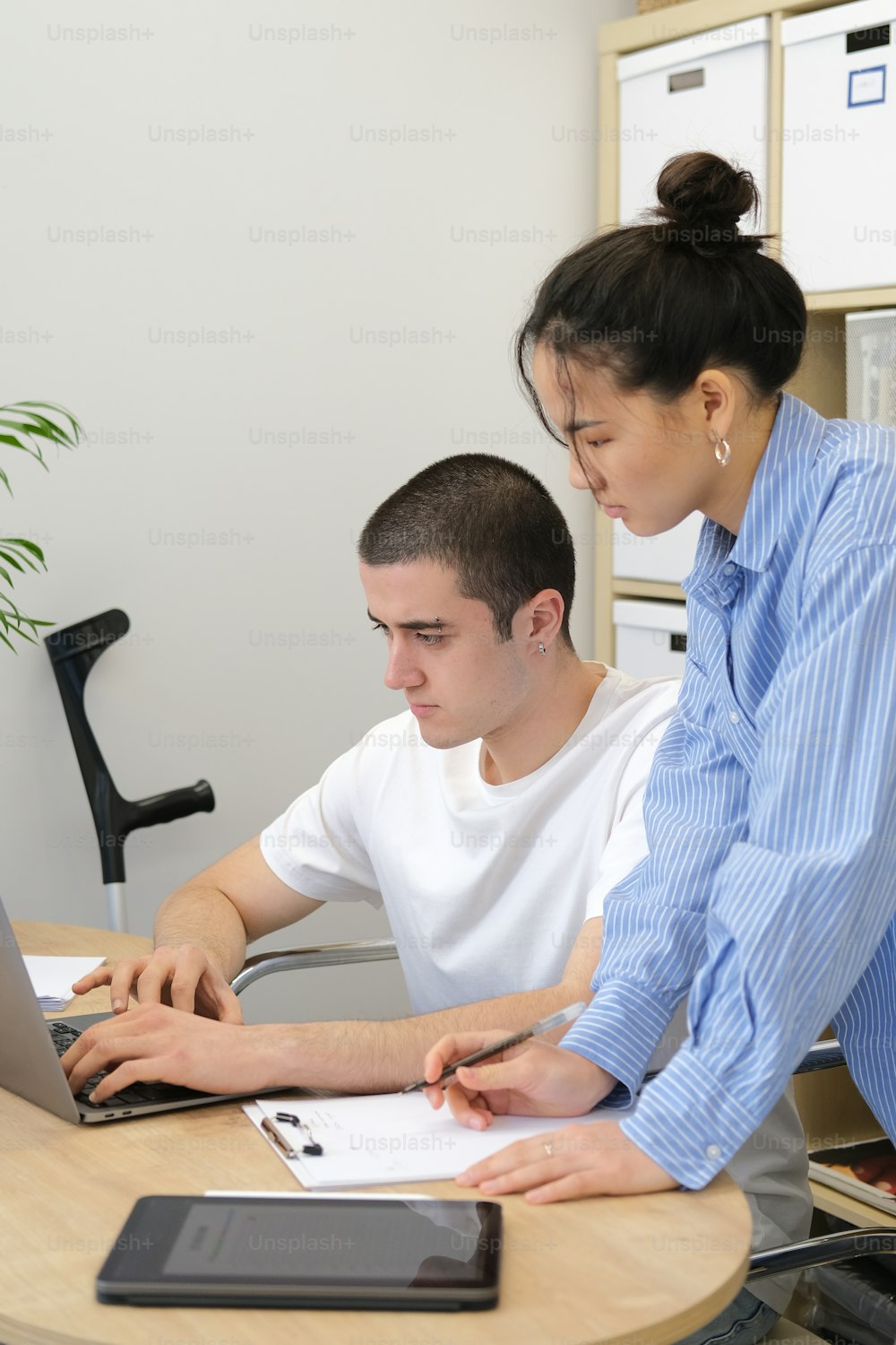 um homem e uma mulher sentados em uma mesa trabalhando em um laptop