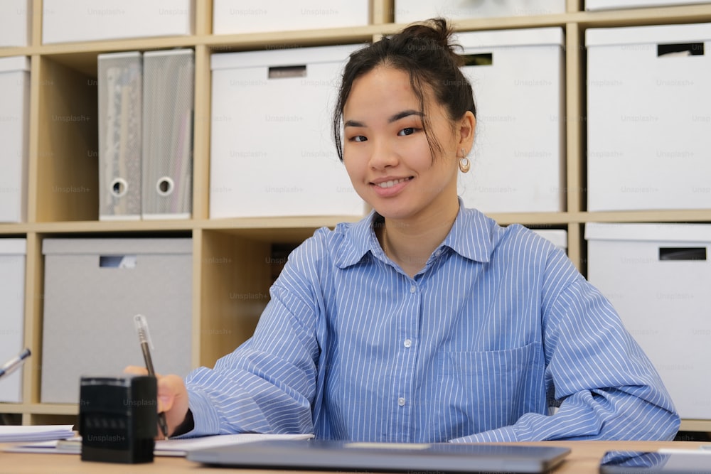 a woman sitting at a desk with a pen in her hand