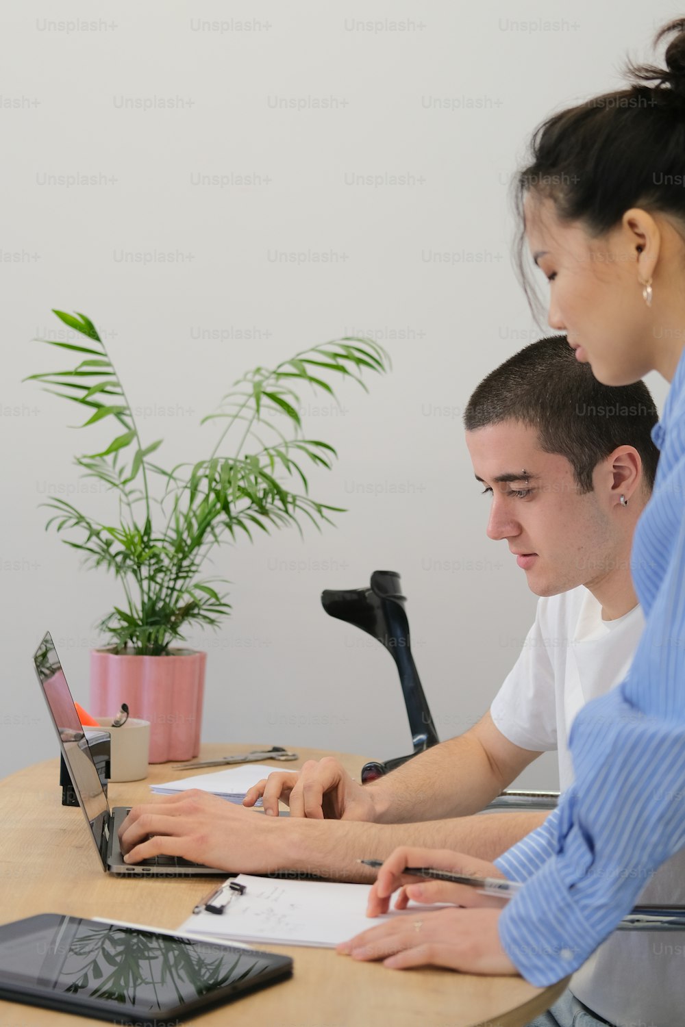 Un homme et une femme assis à une table travaillant sur un ordinateur portable