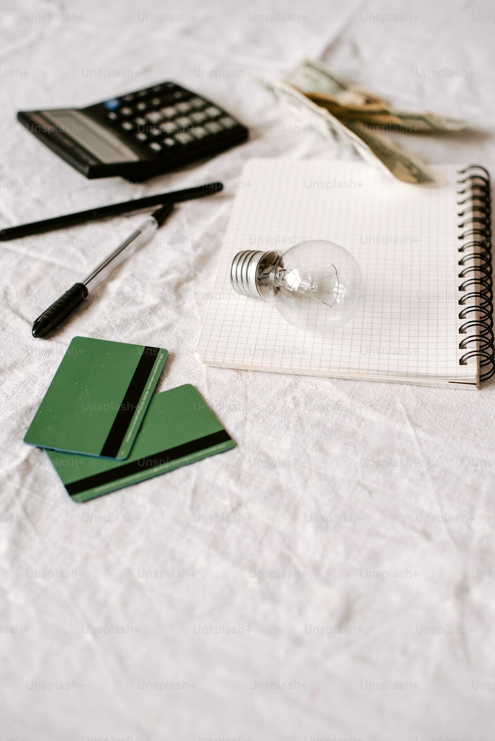 um bloco de notas, caneta, calculadora e uma lâmpada em um