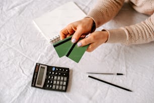 uma pessoa segurando um pedaço de papel ao lado de uma calculadora