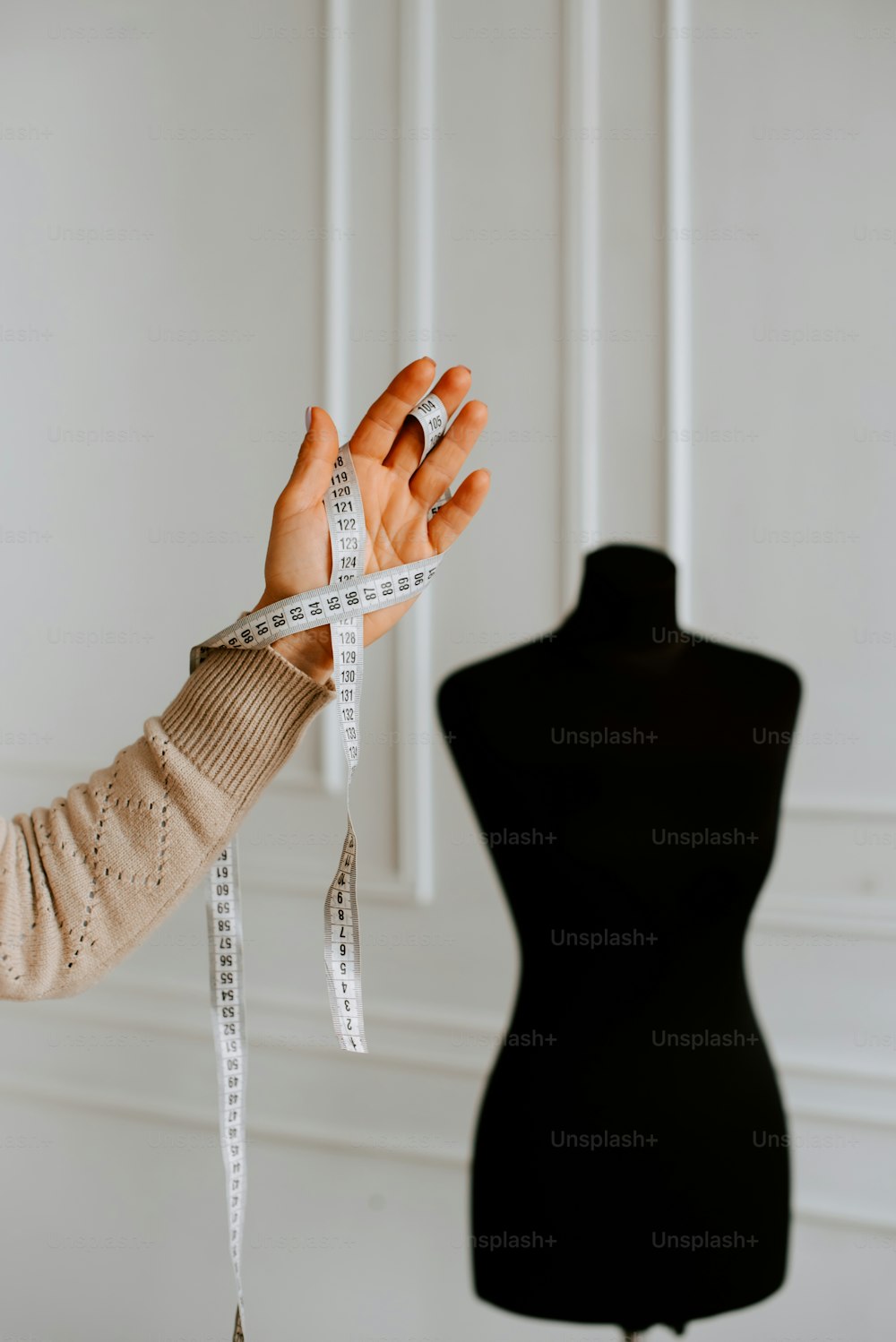 a woman holding a measuring tape in front of a mannequin