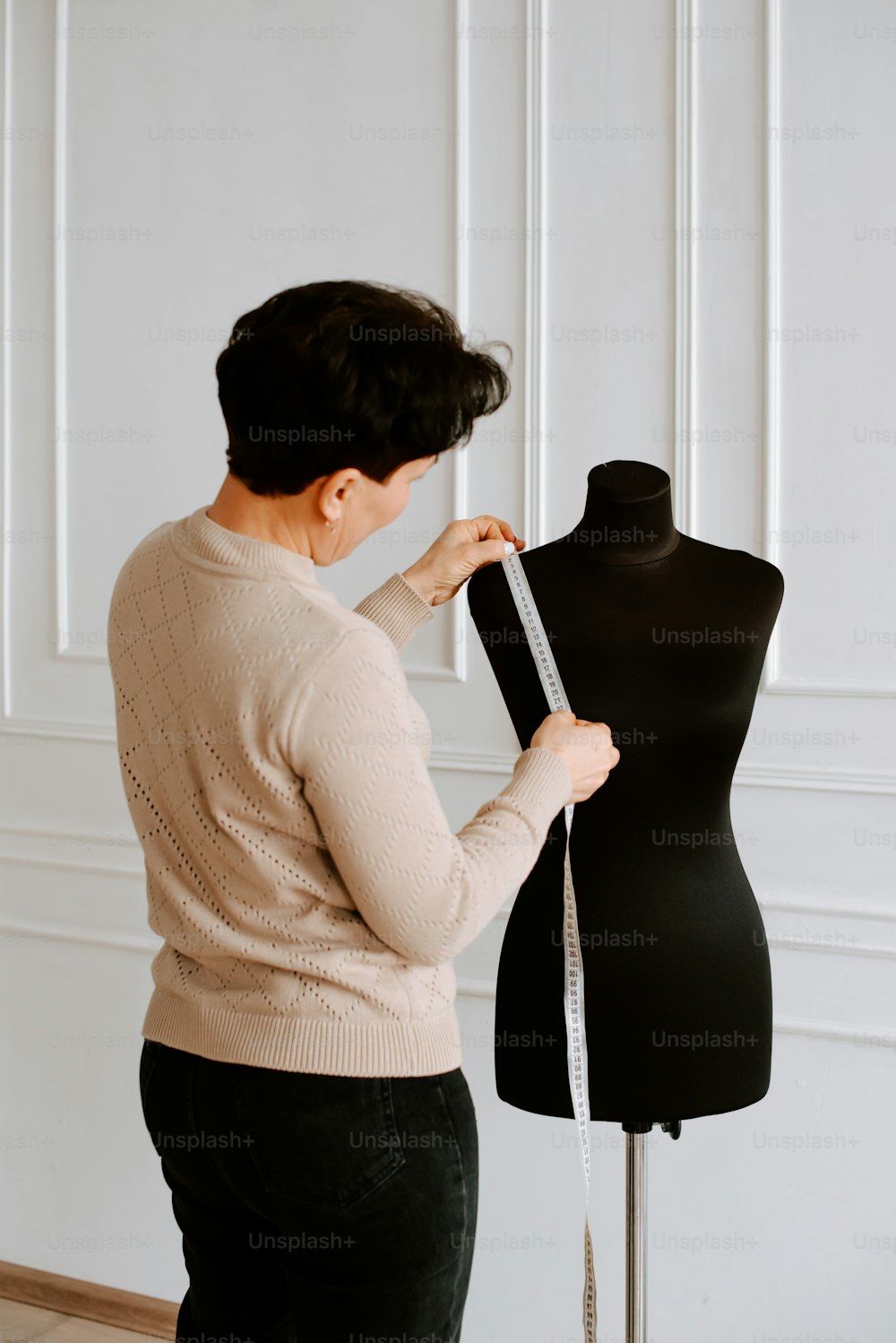 a woman measuring a dress on a mannequin