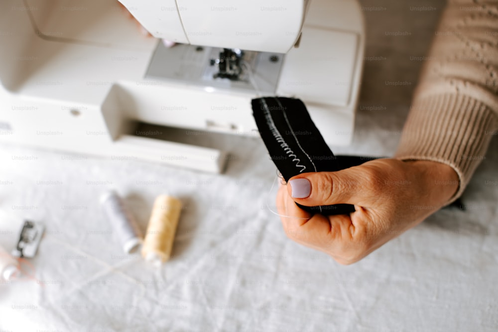 uma pessoa usando uma máquina de costura para costurar um pedaço de tecido