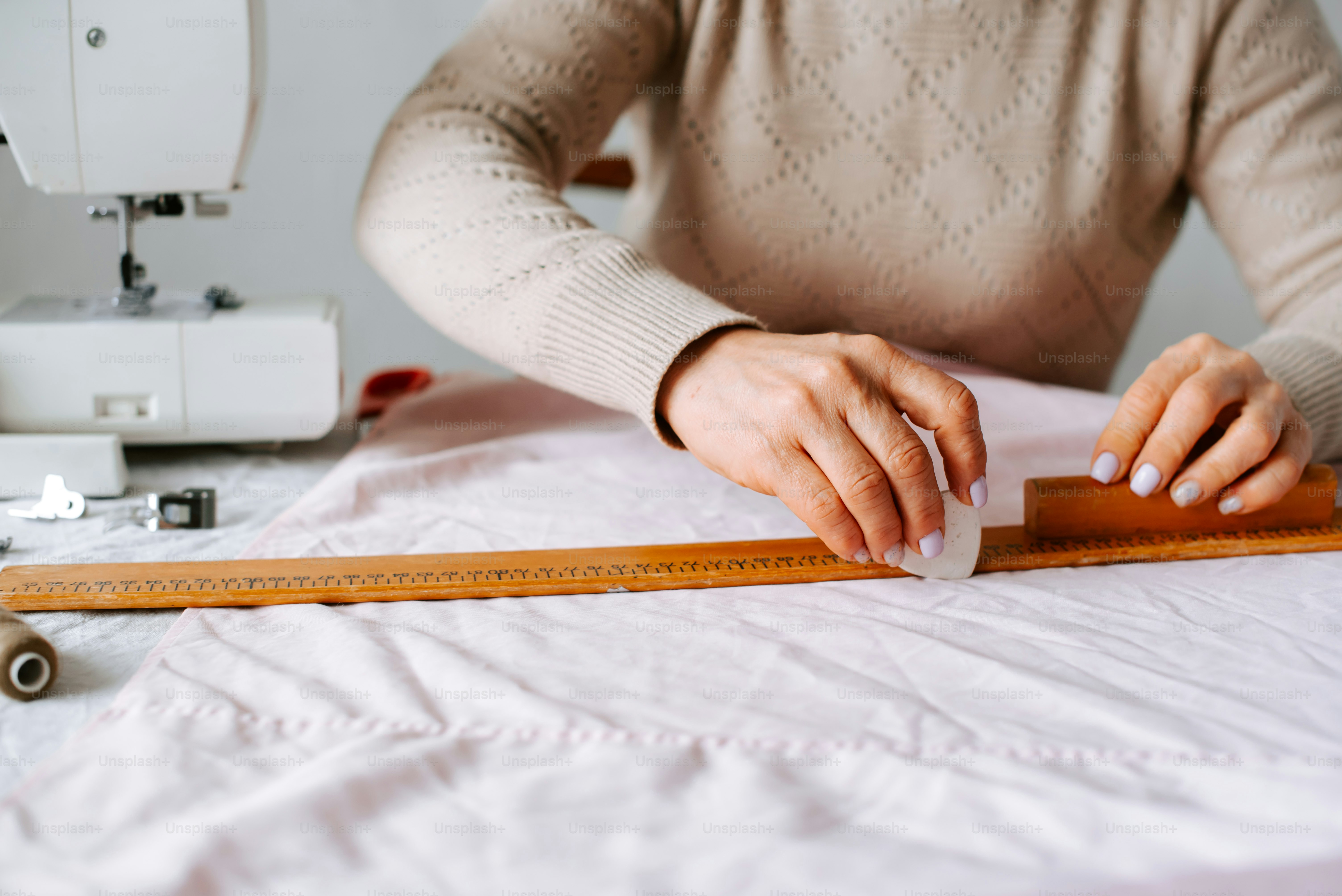 A woman is using a ruler to measure a piece of fabric photo ...