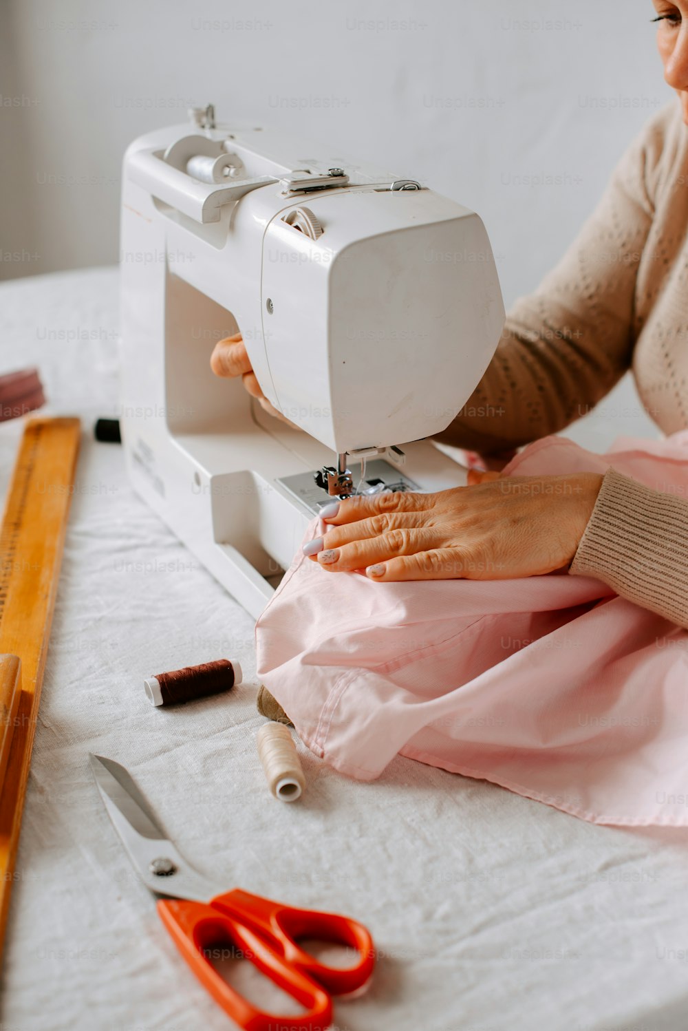 Eine Frau, die mit einer Nähmaschine ein rosa Kleid näht