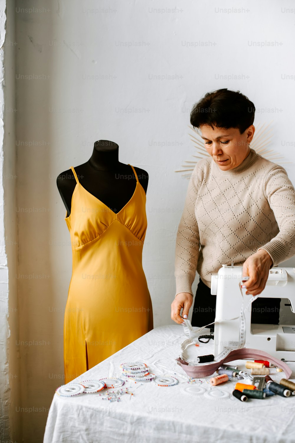 Une femme en robe jaune confectionne une robe