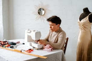Eine Frau sitzt an einem Tisch und arbeitet an einer Nähmaschine