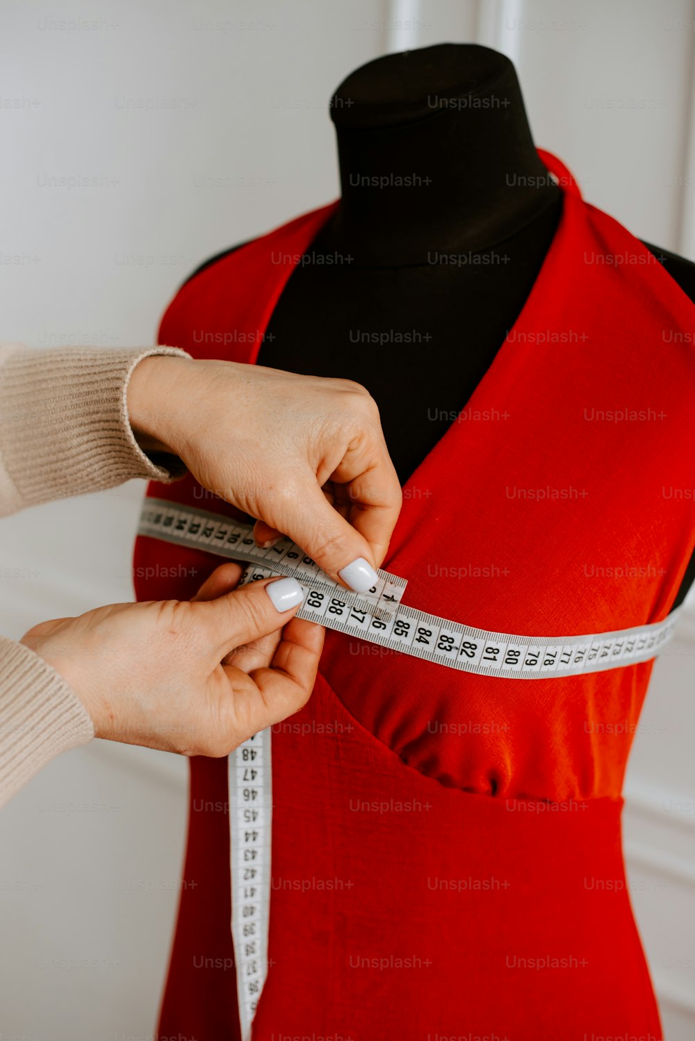 a woman measuring a dress on a mannequin