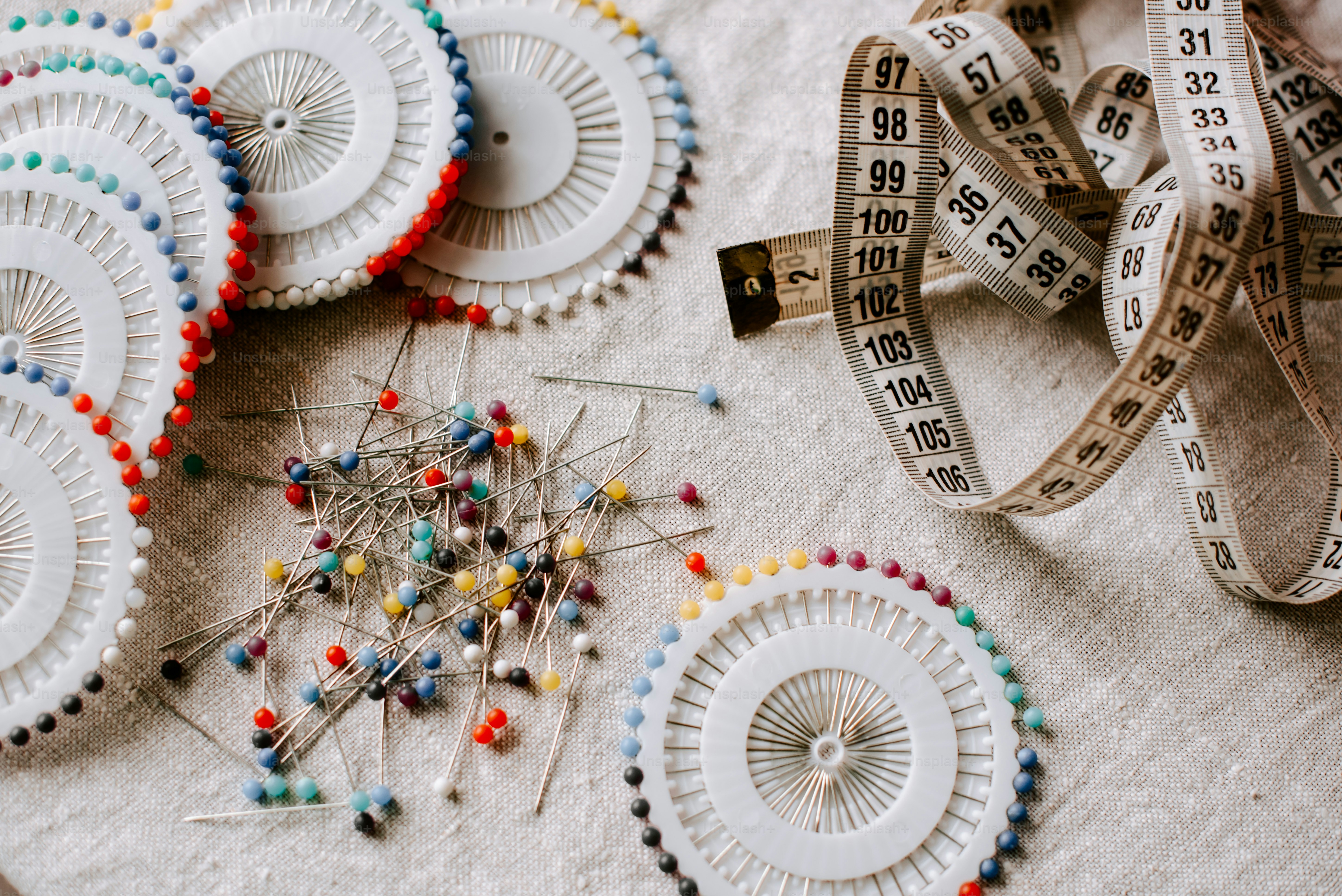 a table topped with lots of pins and a measuring tape