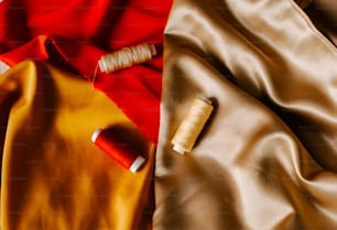 two spools of thread sitting on top of a satin material