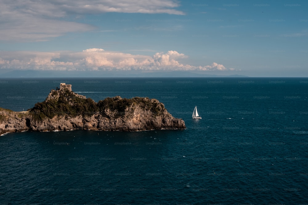 a sailboat in the ocean near a small island