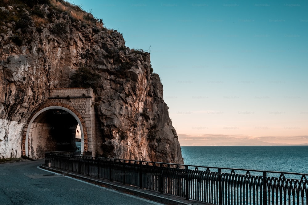 a road going into a tunnel next to the ocean
