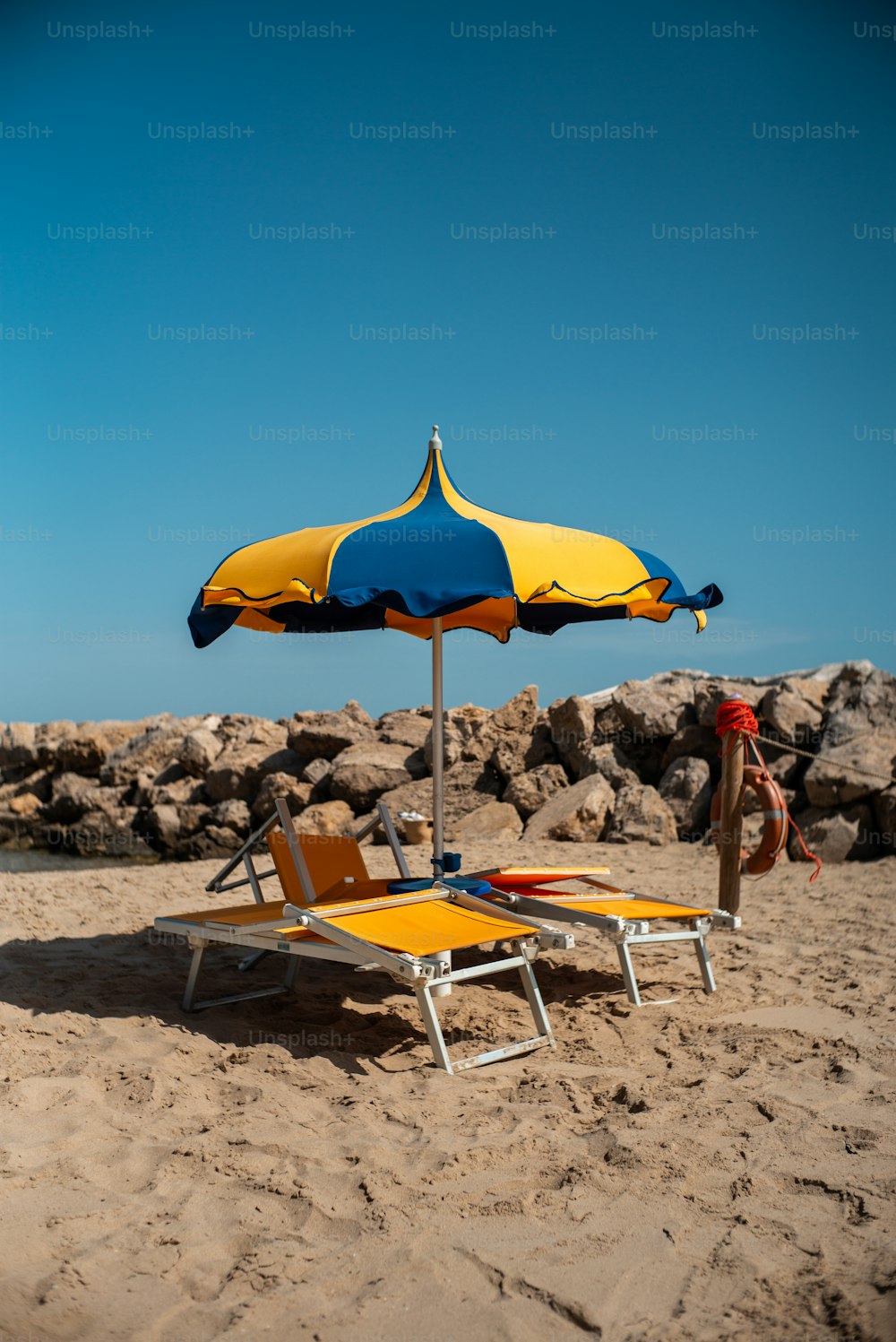 a yellow and blue beach chair sitting on top of a sandy beach