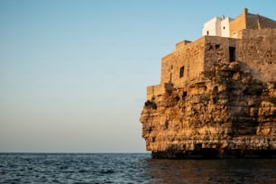 a large stone building sitting on top of a cliff next to the ocean