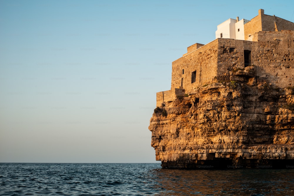 海の隣の崖の上に座っている大きな石造りの建物