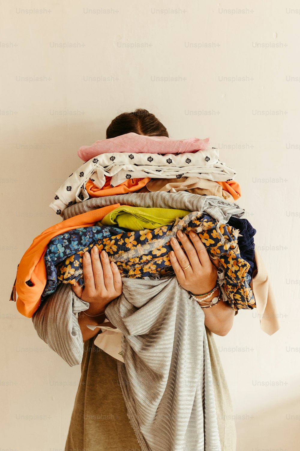 Una mujer sosteniendo un montón de ropa encima de su cabeza