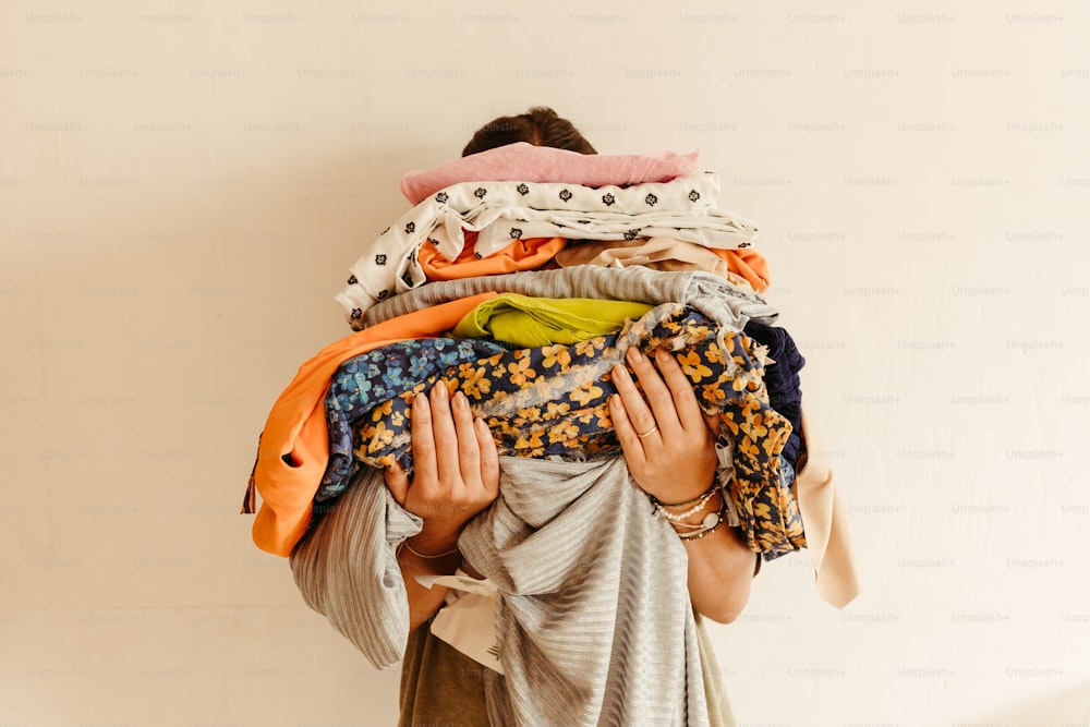 Una mujer cargando un montón de ropa en la espalda
