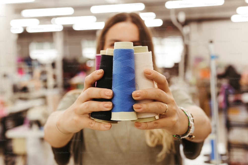 a woman holding a blue and black spool of thread