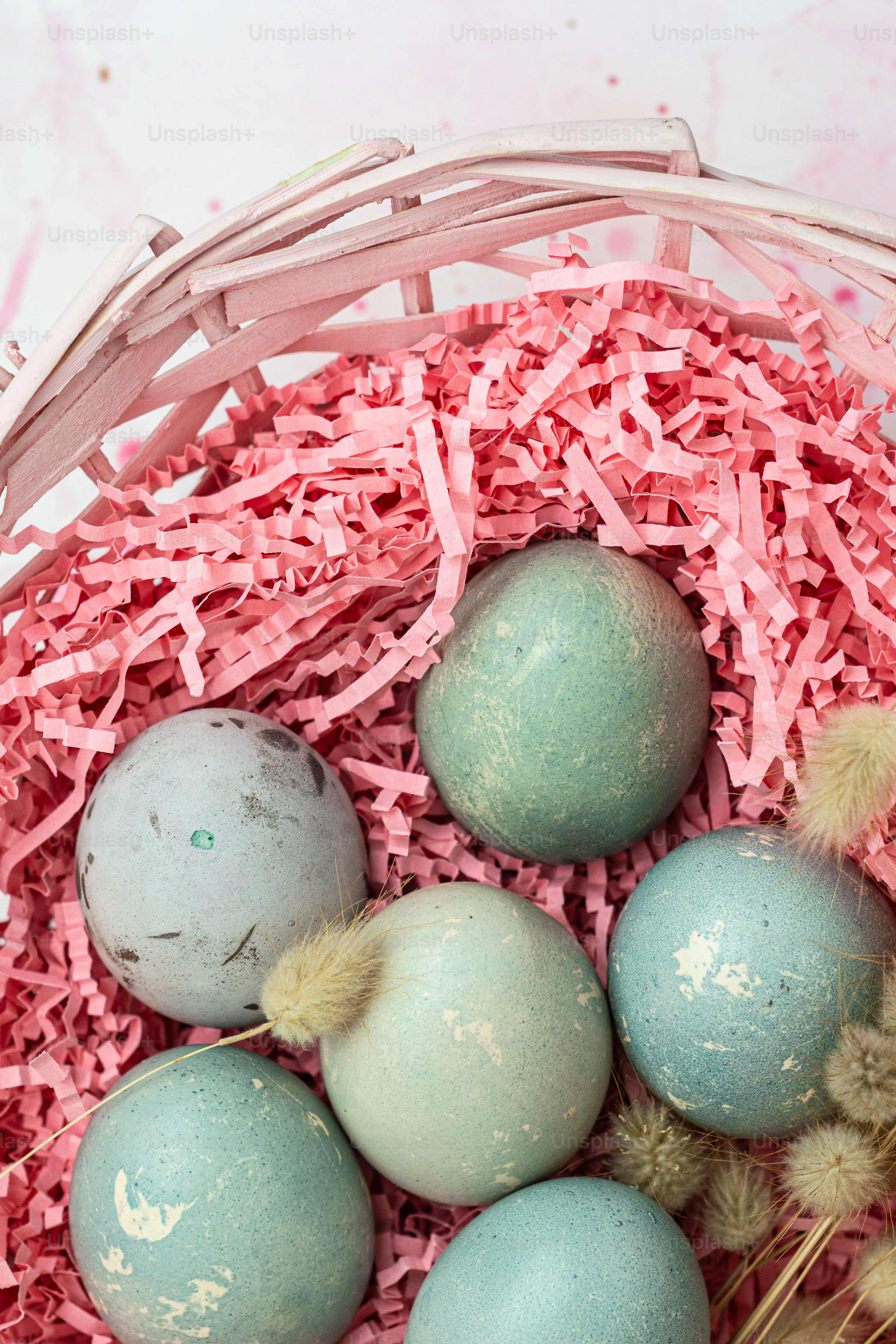 a basket filled with blue and green eggs
