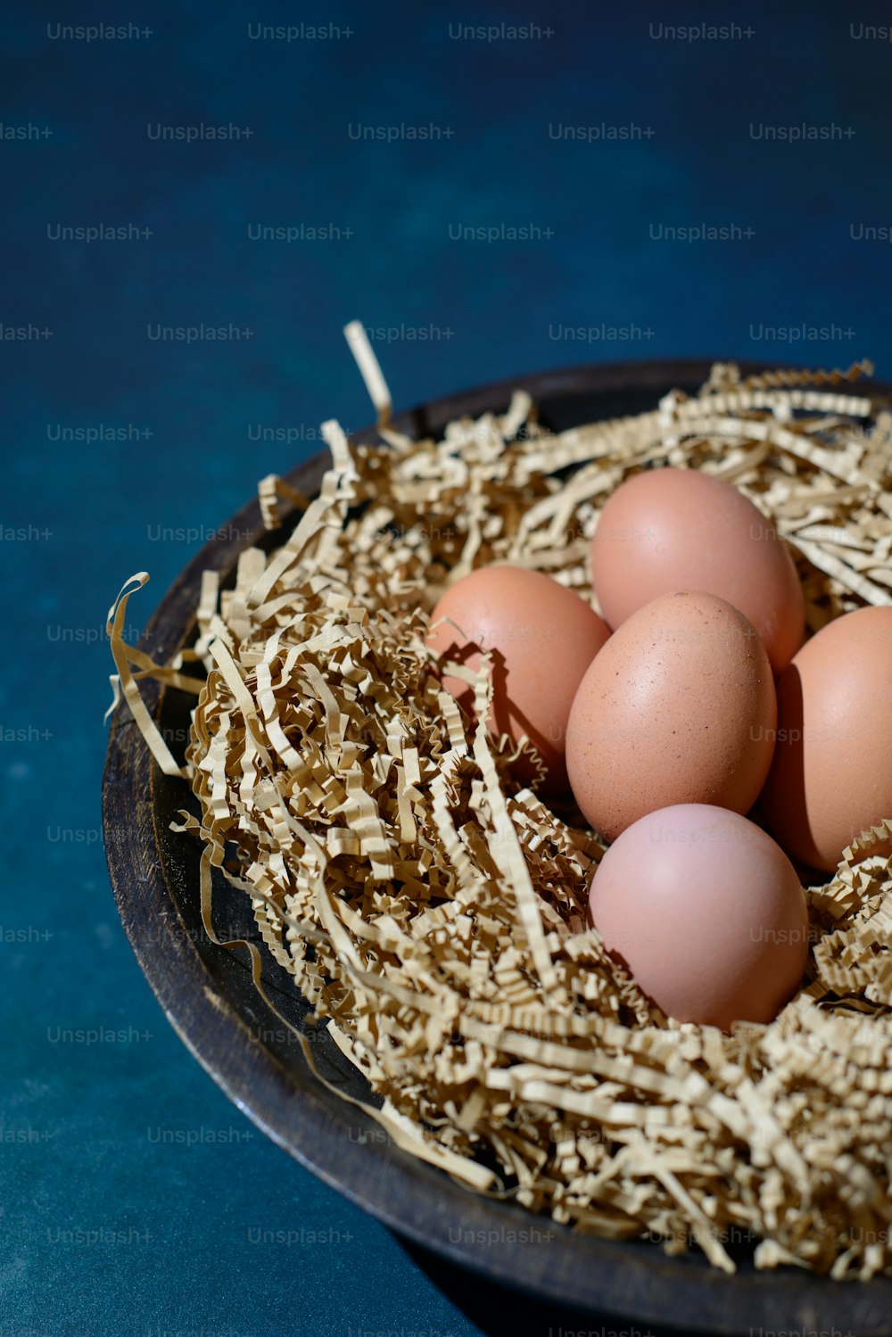 four eggs in a nest of hay on a table