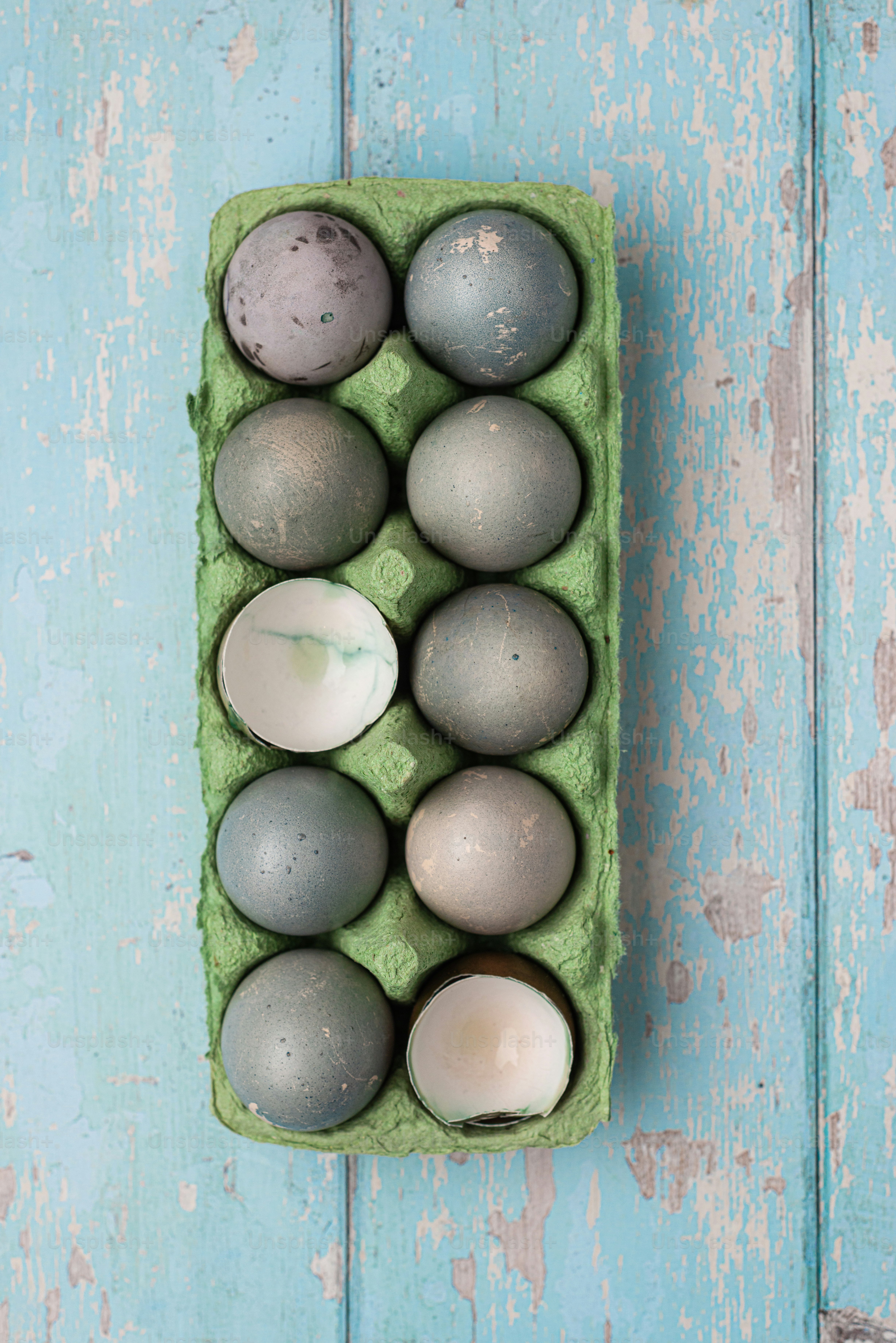 a green carton filled with gray and white eggs