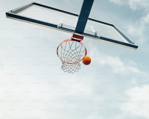 Ein Basketball, der durch den Reifen mit einem Himmelshintergrund geht