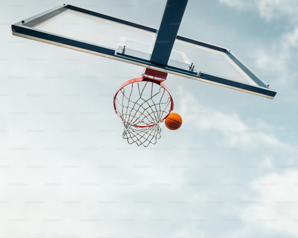 Una pelota de baloncesto atravesando el aro con un fondo de cielo