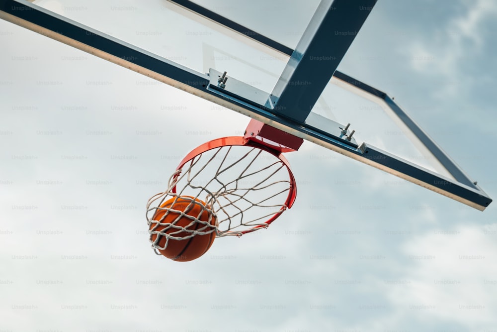 uma bola de basquete atravessando a rede de um aro de basquete