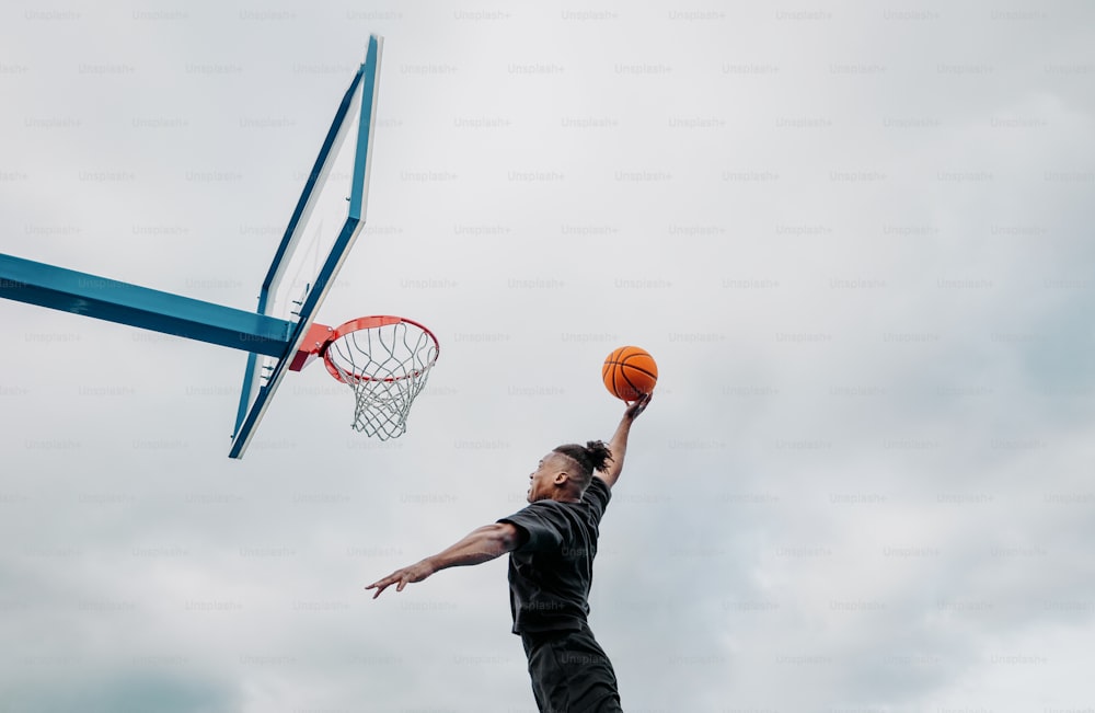 um homem está jogando basquete em um dia nublado