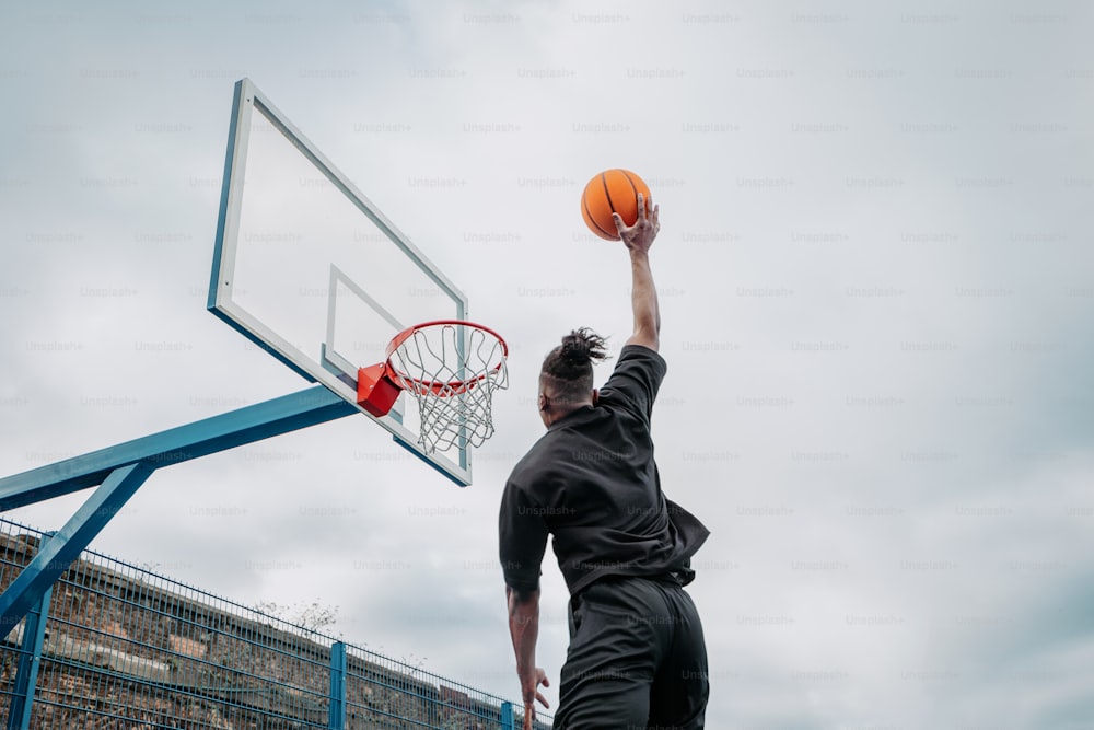 um homem mergulhando uma bola de basquete em um aro