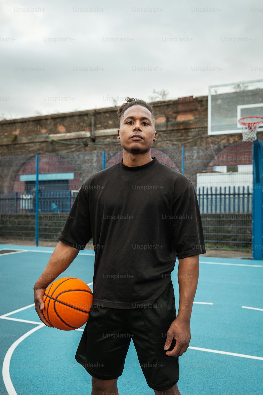 Un homme debout sur un terrain de basket-ball tenant un ballon de basket-ball