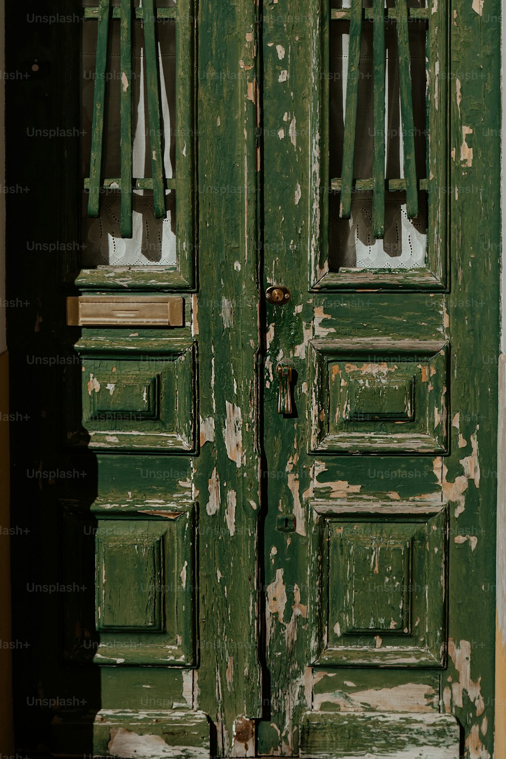 a close up of a green door with peeling paint