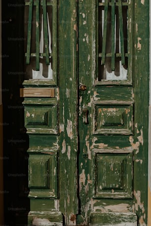 a close up of a green door with peeling paint