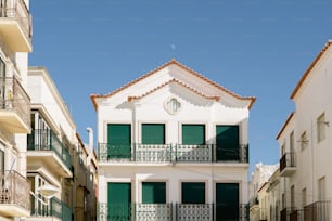 緑のシャッターとバルコニーのある白い建物