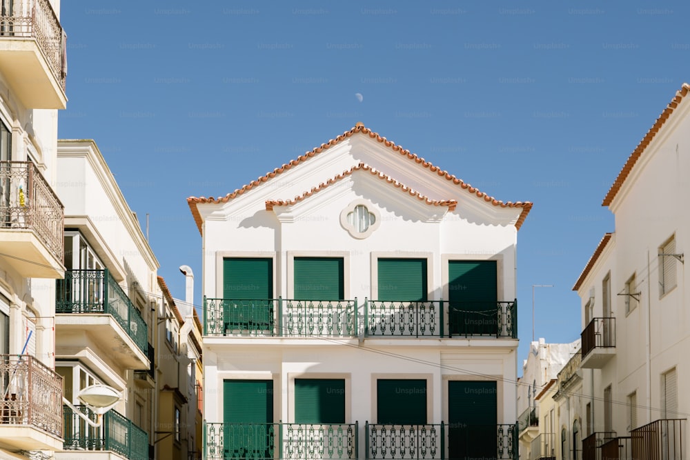 a white building with green shutters and balconies