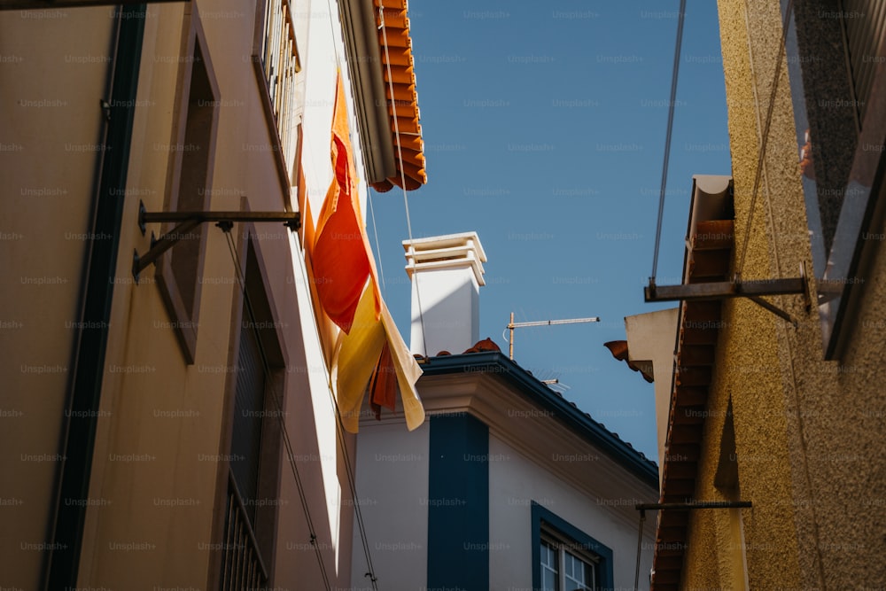 an orange and yellow flag hanging from the side of a building