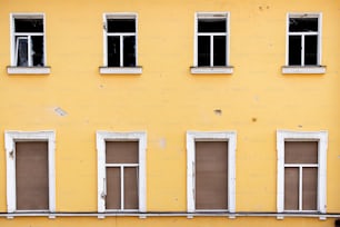 un edificio giallo con quattro finestre e una panchina di fronte