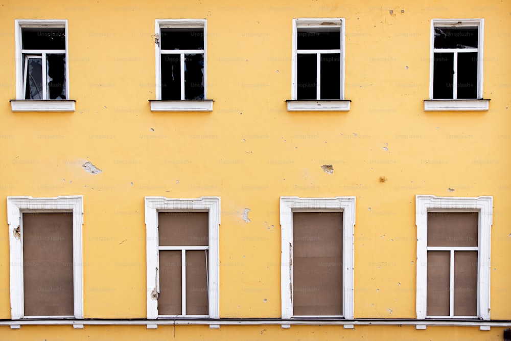 a yellow building with four windows and a bench in front of it