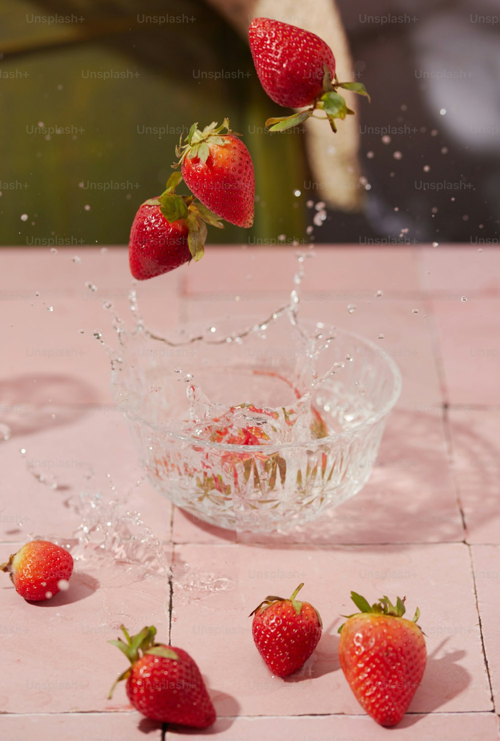 fresas cayendo en un recipiente con agua sobre una mesa