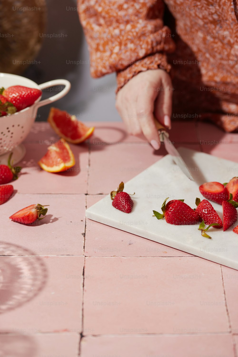 a person cutting strawberries on a cutting board